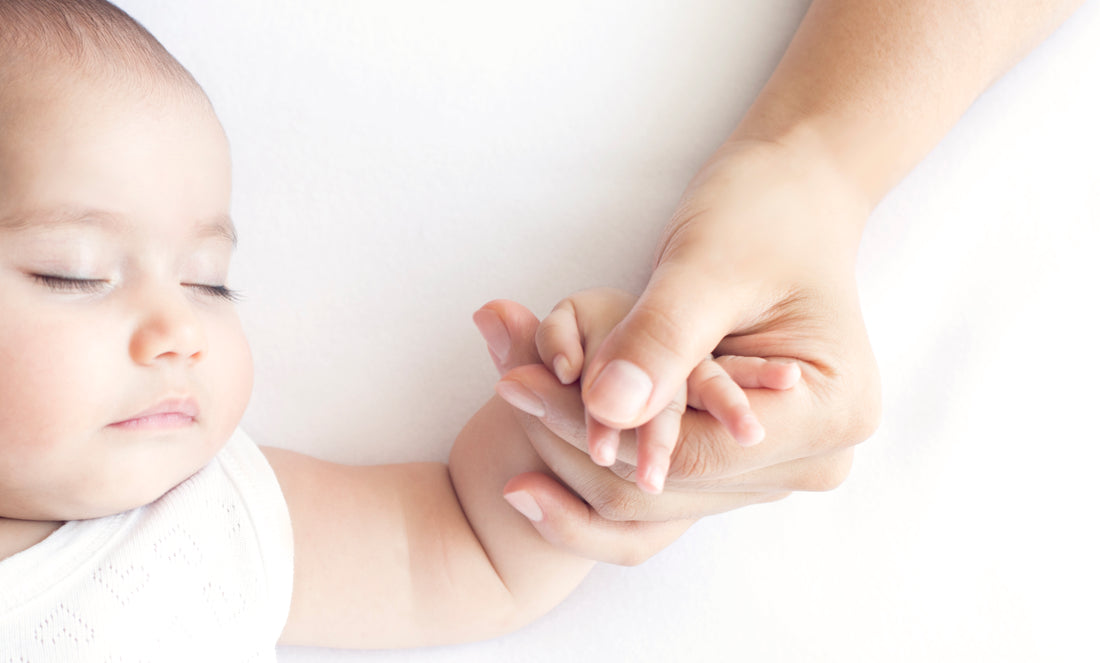 Sleeping baby with mother holding hand | Safe Sleep Space