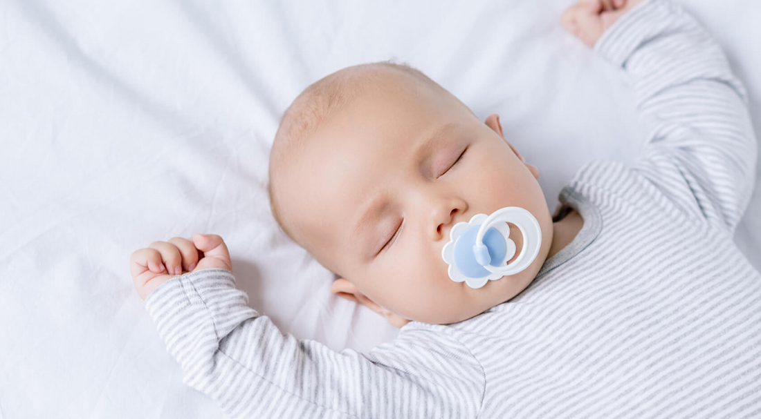Baby sleeping on bed with dummy in its mouth | Safe Sleep Space