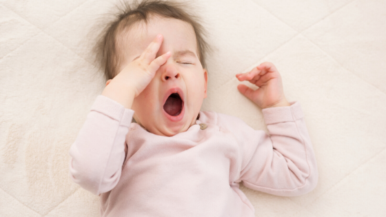 Toddler laying on bed and yawning | Safe Sleep Space