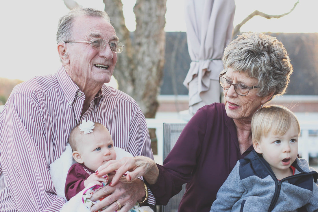 Grandparents sitting with two infant grandchildren | Safe Sleep Space