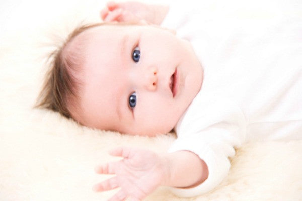 Baby laying on back on a sheepskin rug | Safe Sleep Space