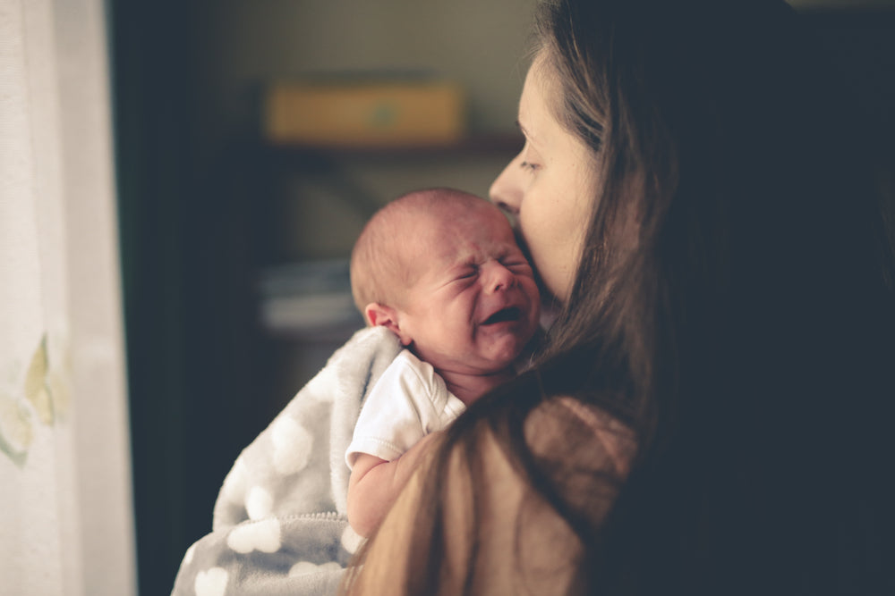 crying newborn in mothers arms