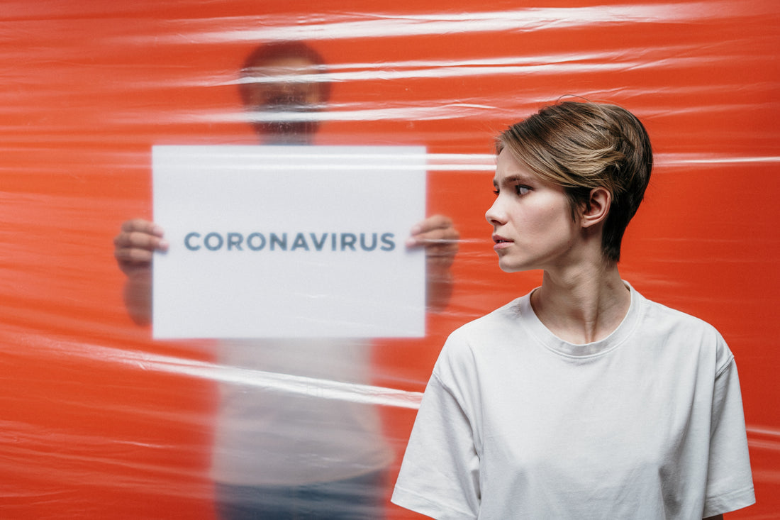 Man holding coronavirus sign behind plastic sheet and woman in foreground | Safe Sleep Space